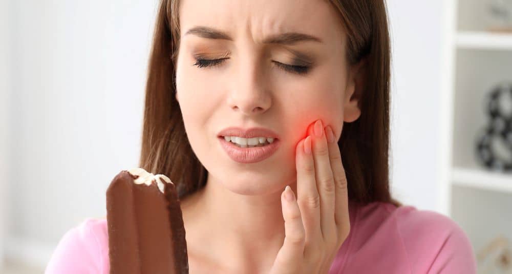 Woman with sensitive tooth holding ice cream.