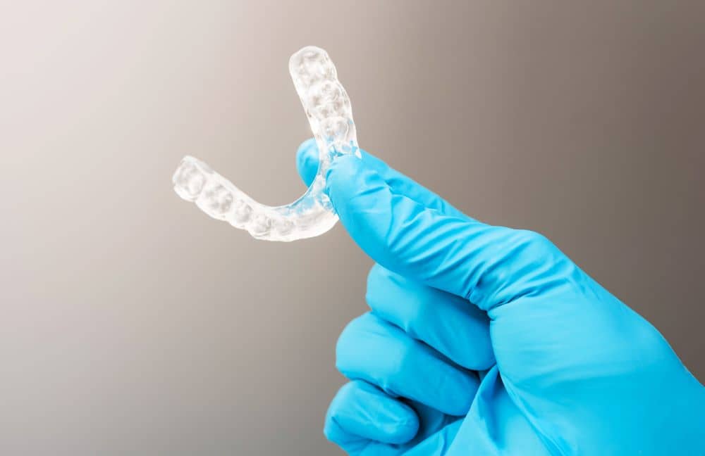 Gloved hand holding bite splint. 