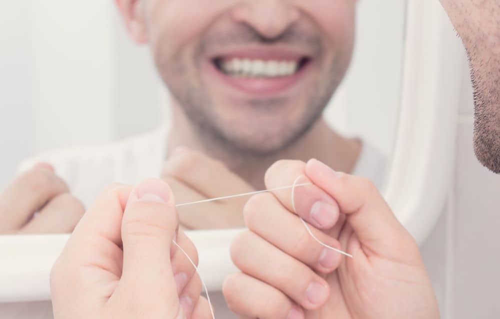 Reflection of a man holding dental floss. 