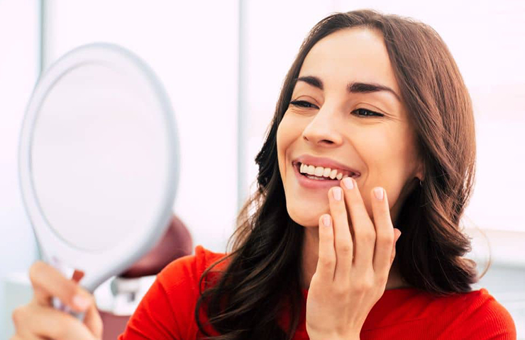 Woman checking her reflection after dental surgery.