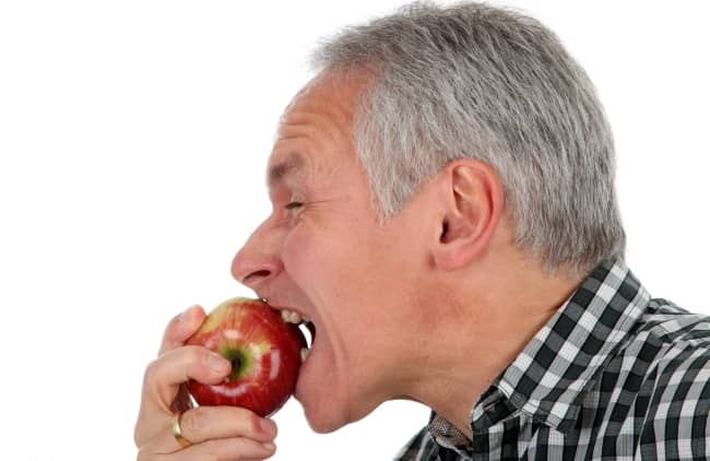 Man with dentures biting an apple.