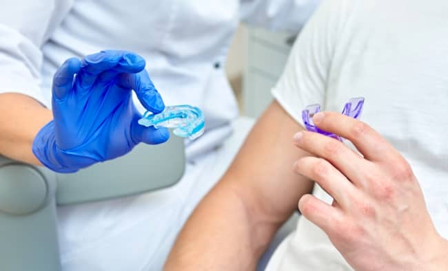 Dentist showing mouthguard to patient.