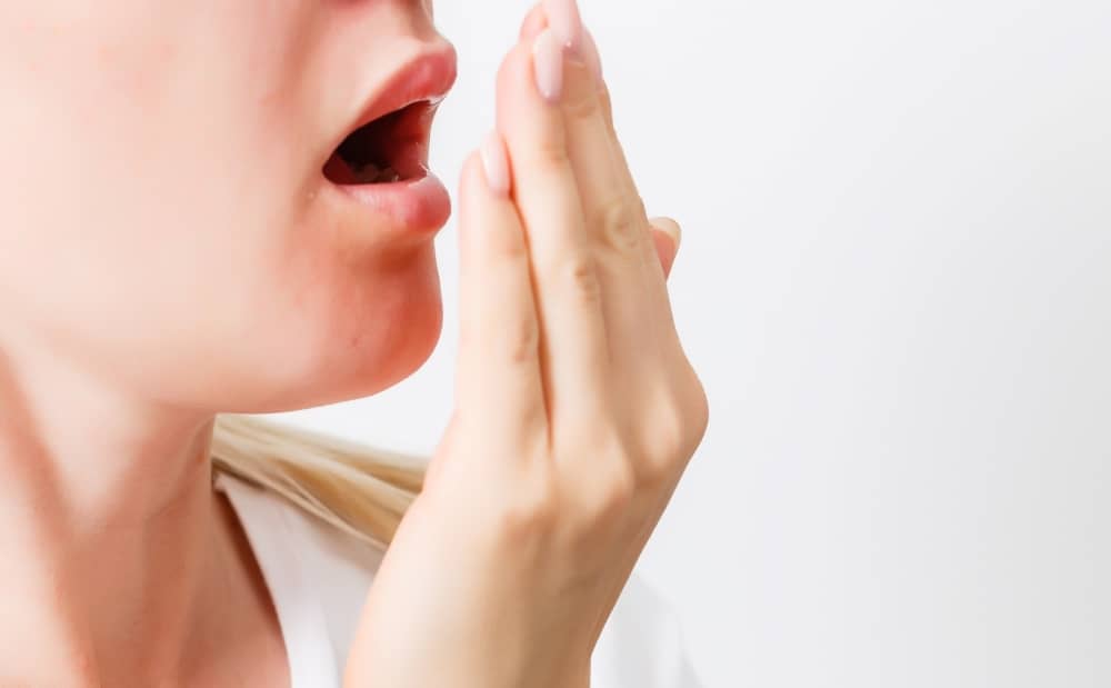 lady checking her breath by breathing into her hand