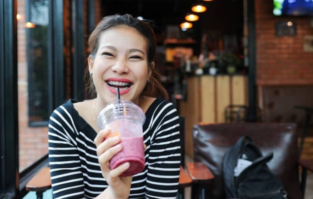 lady with braces drinking a drink