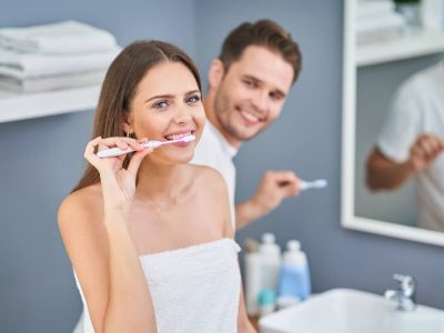 A young couple brushing their teeth.