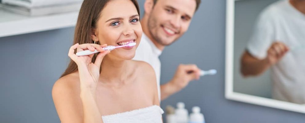 A young couple brushing their teeth.