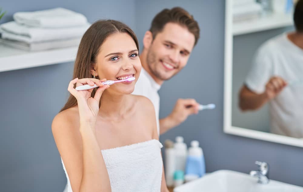 A young couple brushing their teeth.