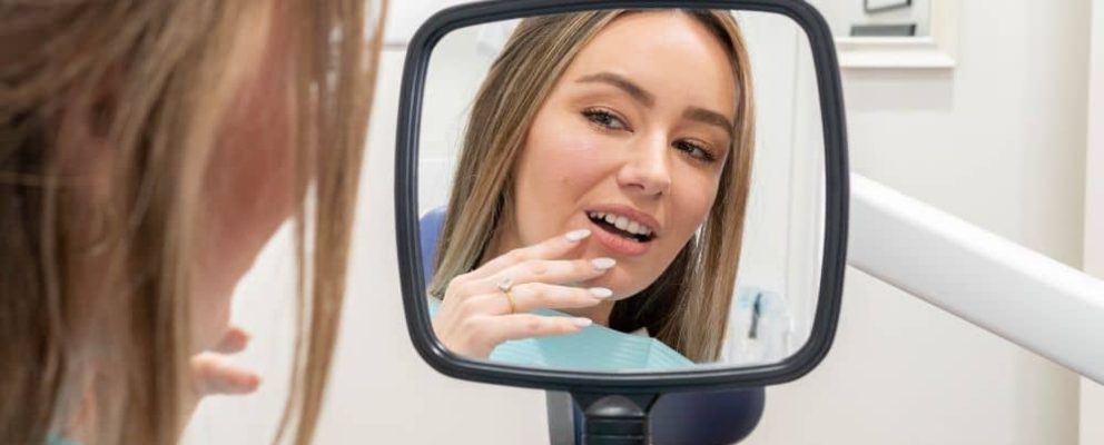 Woman holding a mirror checking her teeth.