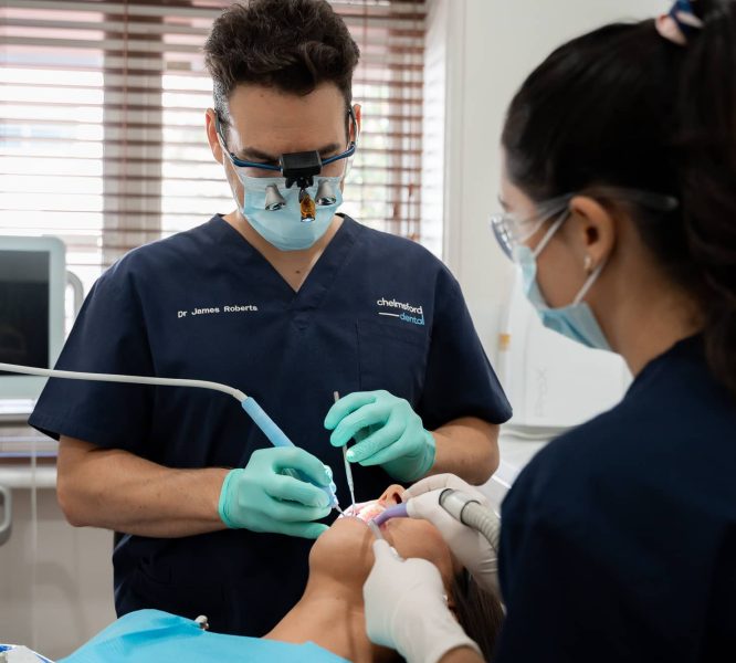 Chelmsford Dental expert dentist Dr James Roberts cleaning teeth with help of dental assistant
