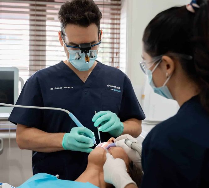 Chelmsford Dental expert dentist Dr James Roberts cleaning teeth with help of dental assistant