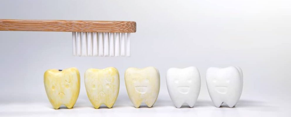 a tooth brush over the top of cartoon stained yellow teeth