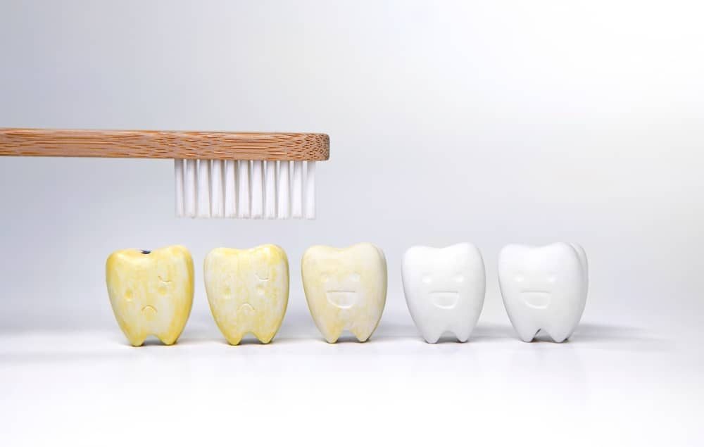 a tooth brush over the top of cartoon stained yellow teeth
