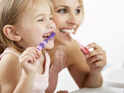 Mother and daughter brushing their teeth.