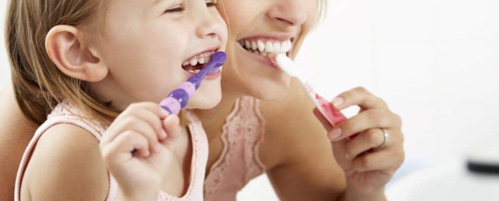 Mother and daughter brushing their teeth.