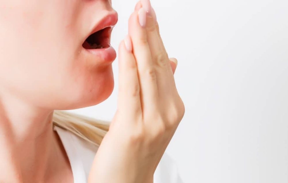 lady checking her breath by breathing into her hand