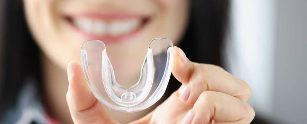 Woman holding mouthguard.