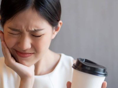 Woman with sensitive tooth experiencing pain while drinking coffee.