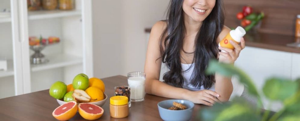 lady smiling holding a bottle of vitamins