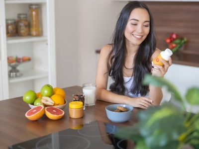 lady smiling holding a bottle of vitamins