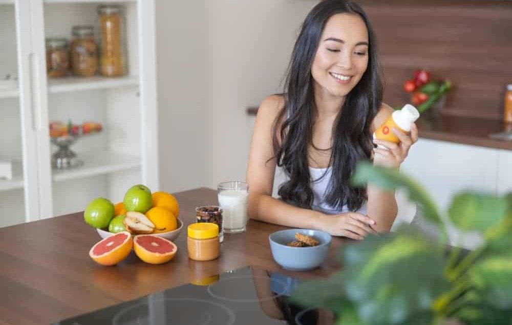 lady smiling holding a bottle of vitamins